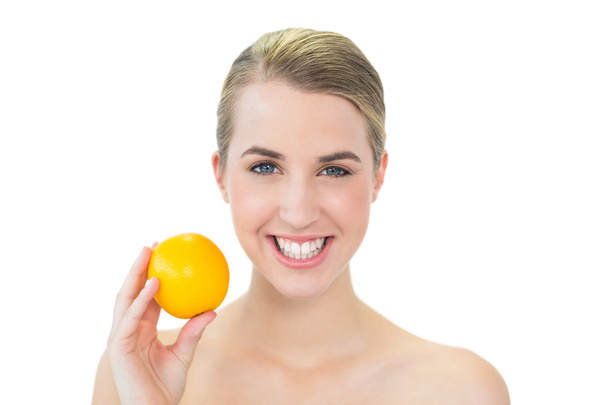 Smiling attractive blonde holding orange - Фото, изображение
