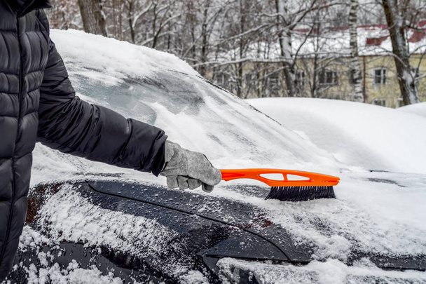 Férfi használ kefe, hogy távolítsa el a havat a kocsiból - Fotó, kép