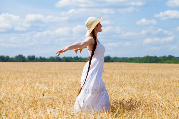 Young brunette woman in white dress walking in a wheat field - Zdjęcie, obraz