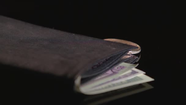 Bitcoin και το νόμισμα χαρτί είναι σε ένα μαύρο πορτοφόλι. Μαύρο φόντο. Κοντινό πλάνο - Πλάνα, βίντεο
