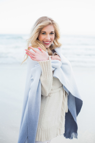 Happy blonde woman in a blanket waving at the camera - Foto, imagen
