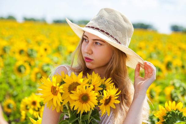 Portrait of a young beautiful girl in a field of sunflowers - Foto, immagini