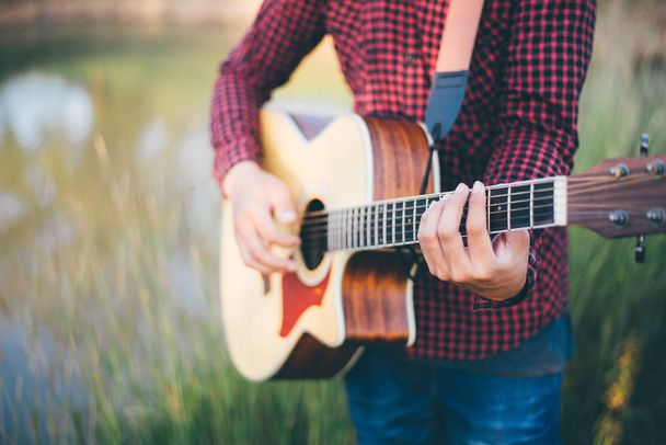 Music in nature, Man playing an acoustic guitar in meadow - Photo, Image
