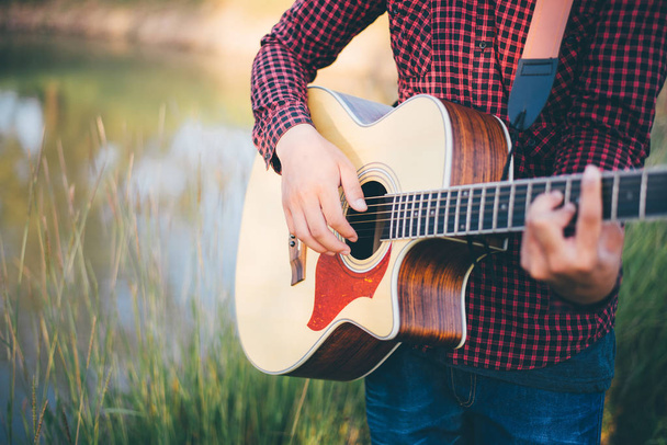 Música na natureza, Homem tocando uma guitarra acústica no prado
 - Foto, Imagem