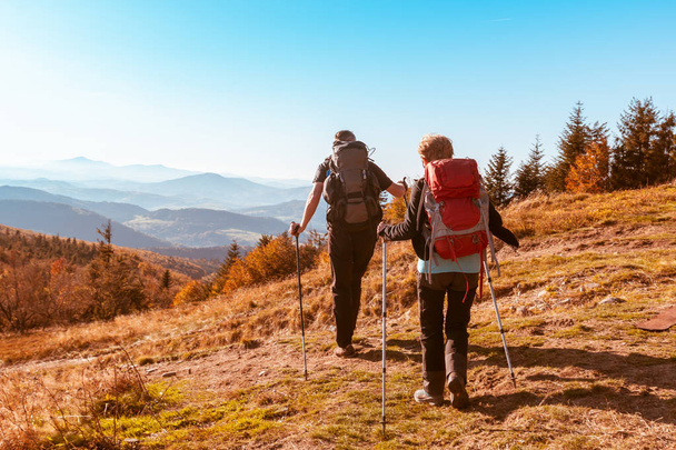 Two old people with large backpacks hike through the autumn  - Photo, Image