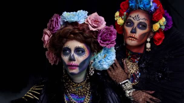 Close-up portret van vrouwelijke modellen met een suikerschedel make-up gekleed met bloemkroon. Halloween concept - Video