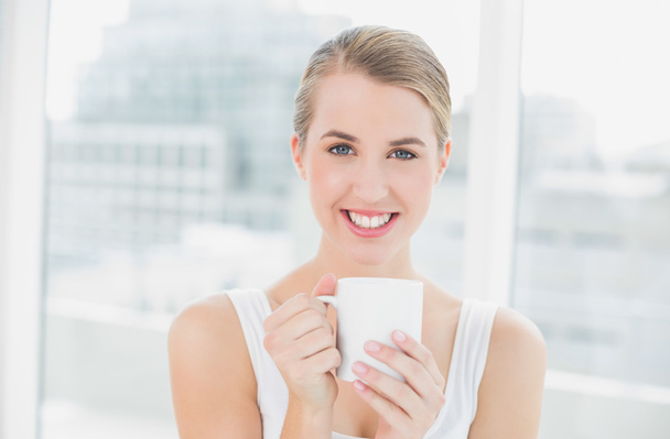 Smiling blond woman holding cup of coffee - Foto, Bild