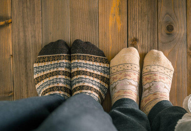 couple with woolen socks sitting on wooden floor - Zdjęcie, obraz