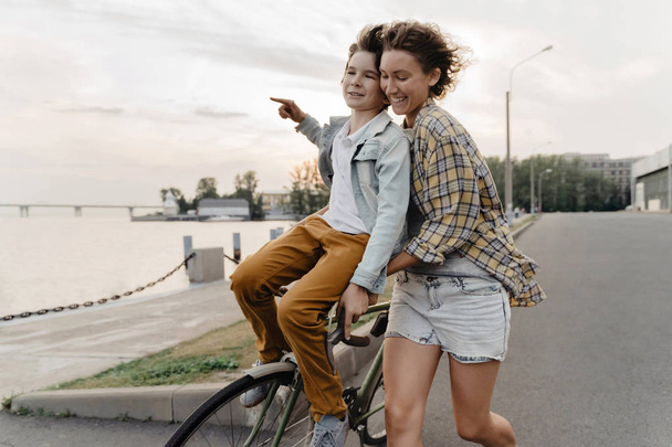Joven madre e hijo divirtiéndose mientras monta bicicleta
. - Foto, Imagen