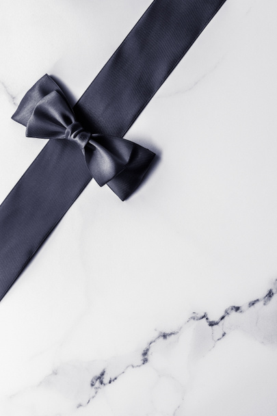 Черная шелковая лента и лук на мраморном фоне, плоский
 - Фото, изображение