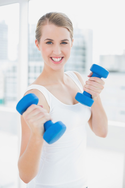 Sporty smiling woman exercising with dumbbells - Фото, изображение