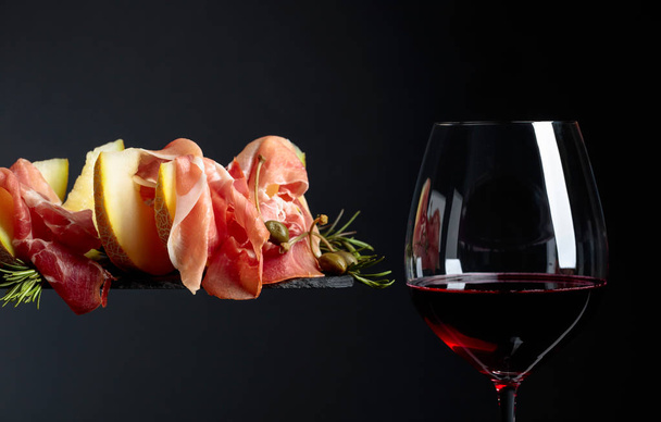 Red wine with prosciutto and melon. - Foto, Bild