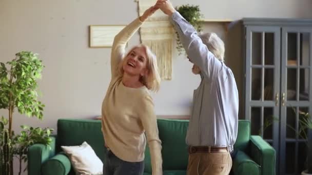 Elderly husband holding hand of wife swirling her dancing together - Video