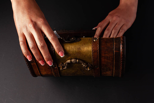A beautiful female hand opens a chest. Beautiful french manicure. - Fotó, kép