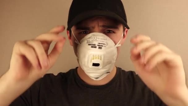 een man met een masker en een pet kijkt bedreigend naar de camera op een beige achtergrond - Video