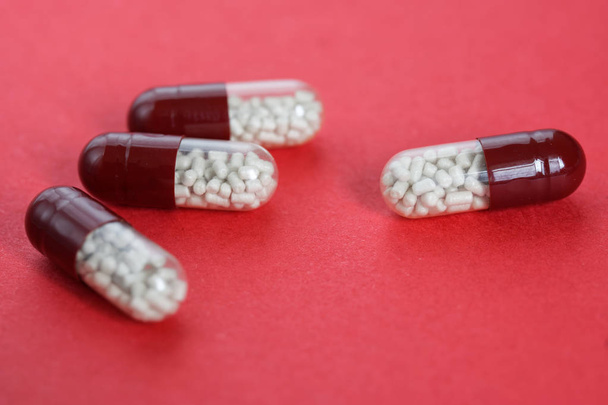 Διαφανείς κάψουλες χάπι με κόκκους βρίσκονται σε ροζ φόντο - Φωτογραφία, εικόνα