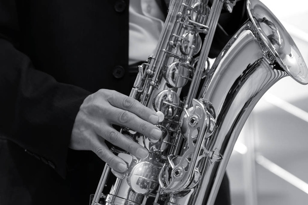 Muž v přísném tmavém obleku hraje na saxofon - Fotografie, Obrázek