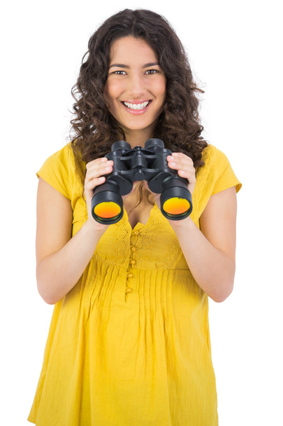 Cheerful casual young woman using binoculars - 写真・画像