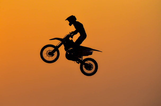 Harjoituspäivä, moottoripyörän motocross-hypyn siluetti auringonlaskun taustalla
. - Valokuva, kuva
