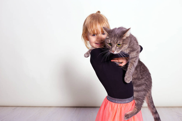 entzückendes kleines blondes Mädchen umarmt niedliches Haustier grau gestromt Kätzchen - Foto, Bild