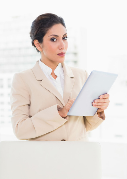 Businesswoman standing behind her chair holding digital tablet - Foto, Bild