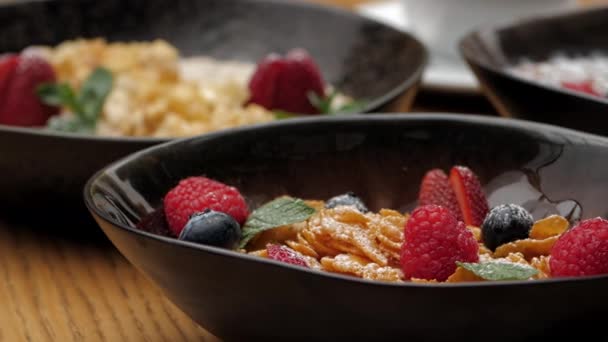 Cornflakes mit frischen Himbeeren, Blaubeeren und Erdbeeren in Keramikschale. Nahaufnahme auf einer Rutsche. - Filmmaterial, Video