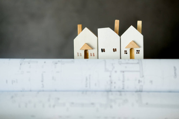 Miniaturhaus auf Papierbündel aufgerollt Baupläne  - Foto, Bild
