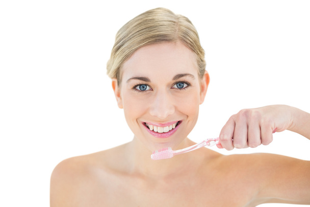 Joyful young blonde woman brushing her teeth - Foto, imagen