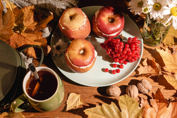Herfstcompositie. Gebakken appels met kwark, cranberry 's, thee en bladeren op tafel. - Foto, afbeelding