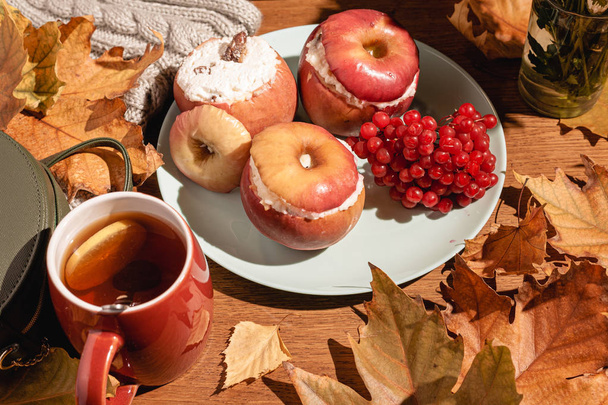 Herfstcompositie. Gebakken appels met kwark, cranberry 's, thee en bladeren op tafel. - Foto, afbeelding