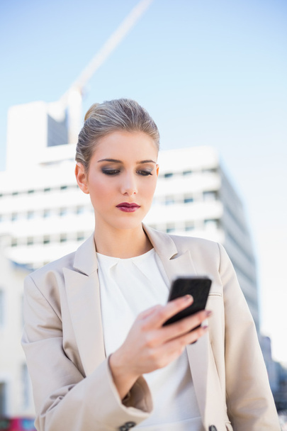 Serious attractive businesswoman sending a text message - Foto, afbeelding