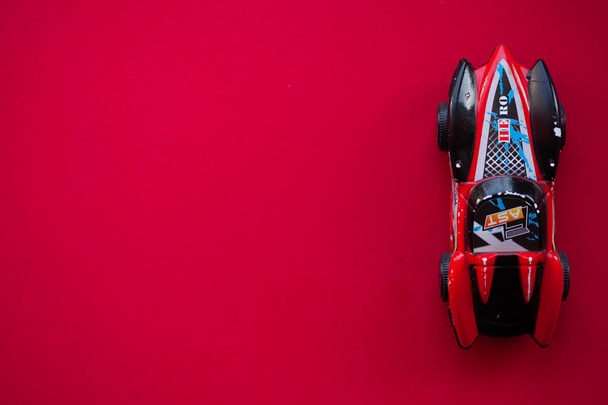 Foto van een speelgoedauto op een rode achtergrond. - Foto, afbeelding