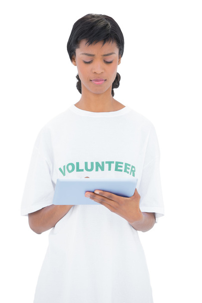 Thoughtful black haired volunteer using a tablet pc - Photo, image