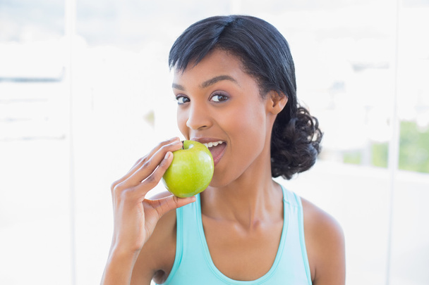 Calm black haired woman eating an apple - Fotoğraf, Görsel