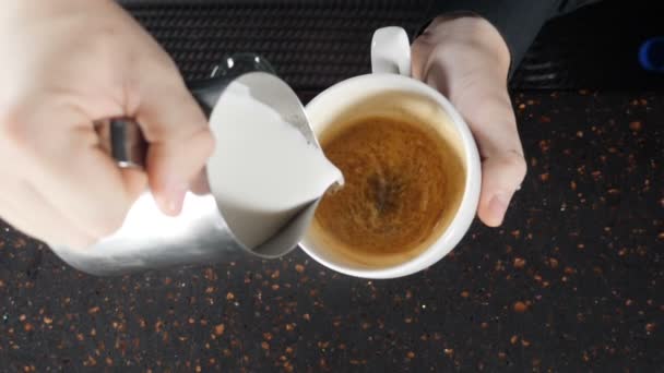 Closeup footage of barista pouring milk into cup, making cappuccino, Bartender prepares a cappuccino Cup and draws pattern of milk. coffee shopconcept. slow motion. hd - Footage, Video
