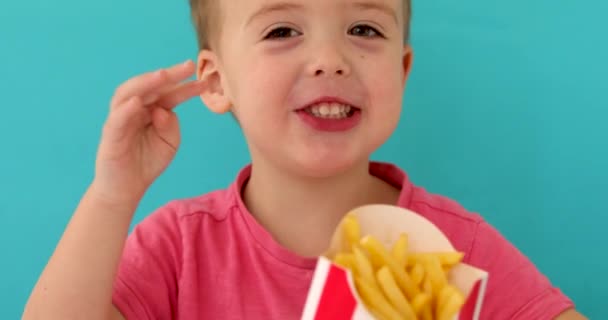 Young boy indoors eating fish and chips smiling - Footage, Video