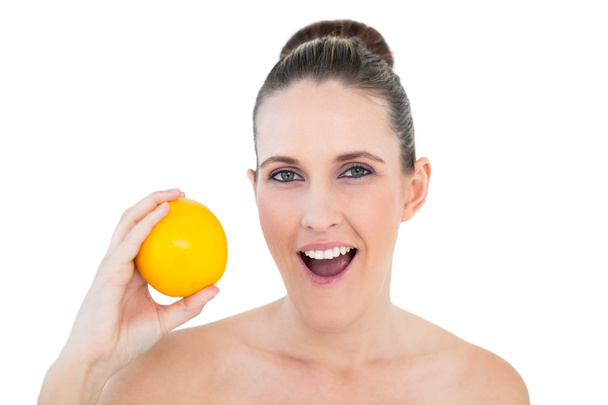 Surprised gorgeous woman holding orange - Foto, Imagen