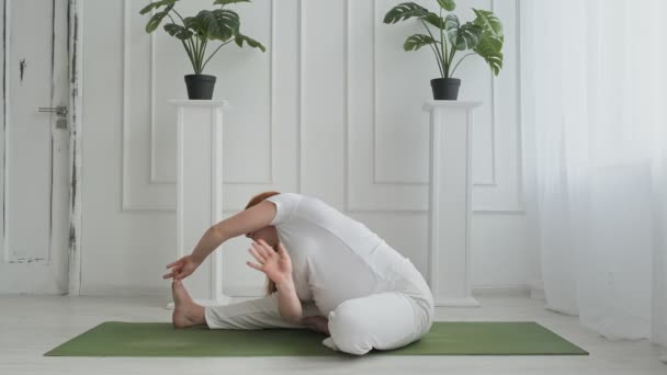 Beautiful pregnant doing yoga on floor. Young pregnant woman stretching - Imágenes, Vídeo