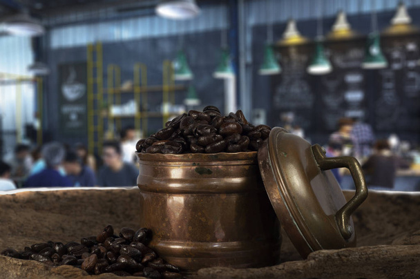 Kávébab egy évjárat réz fém tartályban, elmosódott kávéházi háttérrel. - Fotó, kép