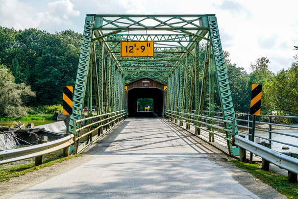 To jest Harpersfield Covered Bridge, który biegnie wzdłuż Grand River w północno-wschodnim Ohio. Most ma ponad sto lat, a samochody wciąż przejeżdżają przez niego każdego dnia.. - Zdjęcie, obraz