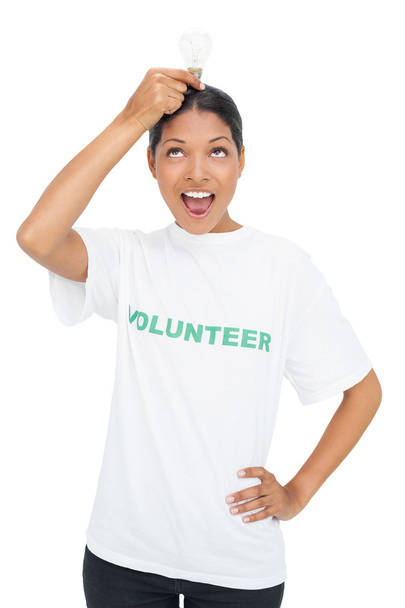 Happy model wearing volunteer tshirt holding light bulb above her head - Photo, image
