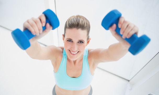 Cheerful blonde woman exercising with dumbbells - Фото, изображение