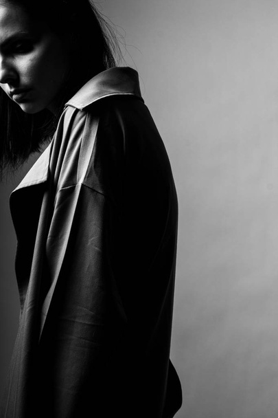 gyönyörű fiatal lány egy árok kabát, fekete-fehér  - Fotó, kép