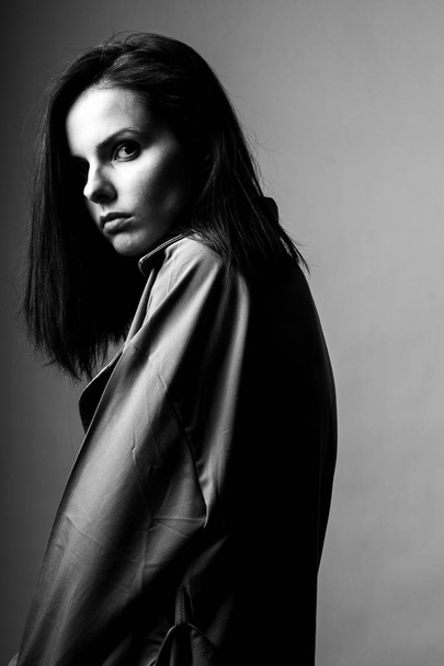 beautiful young girl in a trench coat, black and white  - Фото, изображение