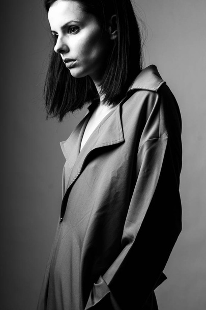 beautiful young girl in a trench coat, black and white  - Фото, зображення