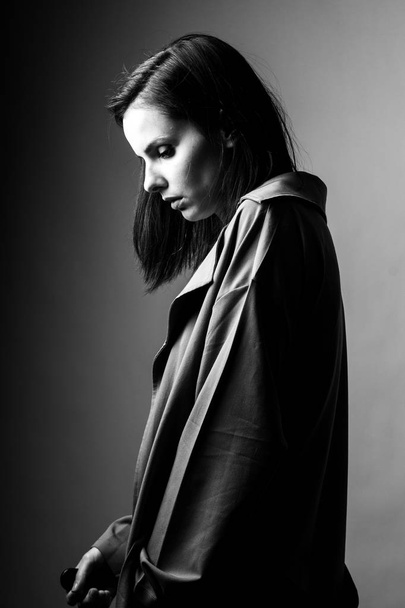 beautiful young girl in a trench coat, black and white  - Фото, изображение