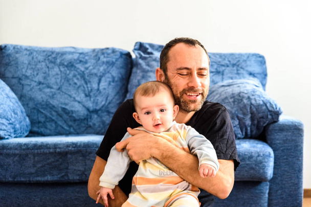 Ο πατέρας κάθεται στο πάτωμα με το μωρό στην αγκαλιά του με τη liv - Φωτογραφία, εικόνα
