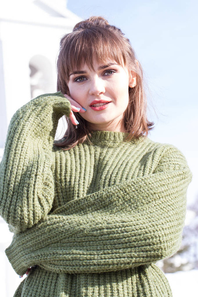 Beautiful young girl in a green sweater on a background of clear blue sky - Fotoğraf, Görsel