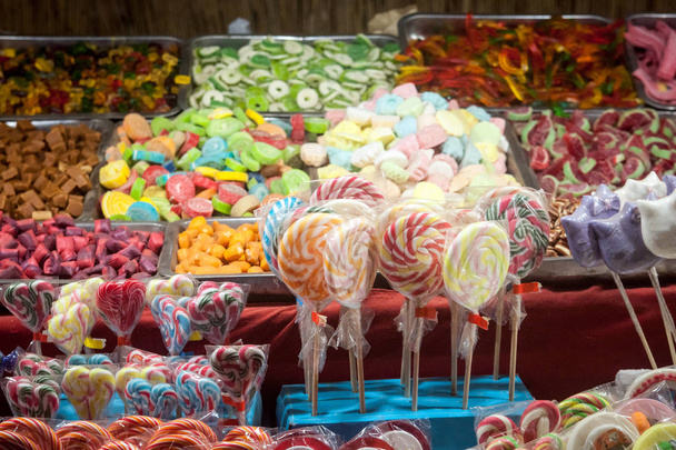 Caramelos, principalmente dulces y piruletas de goma, diversificados, exhibidos en una tienda de dulces durante un carnaval o una feria
 - Foto, imagen