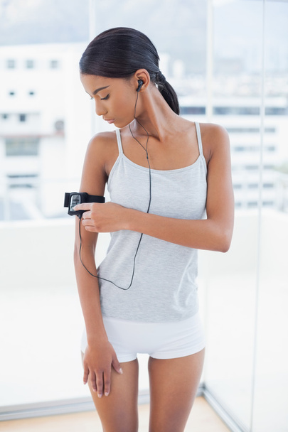 Pretty model in sportswear changing song on her mp3 - Foto, Imagem